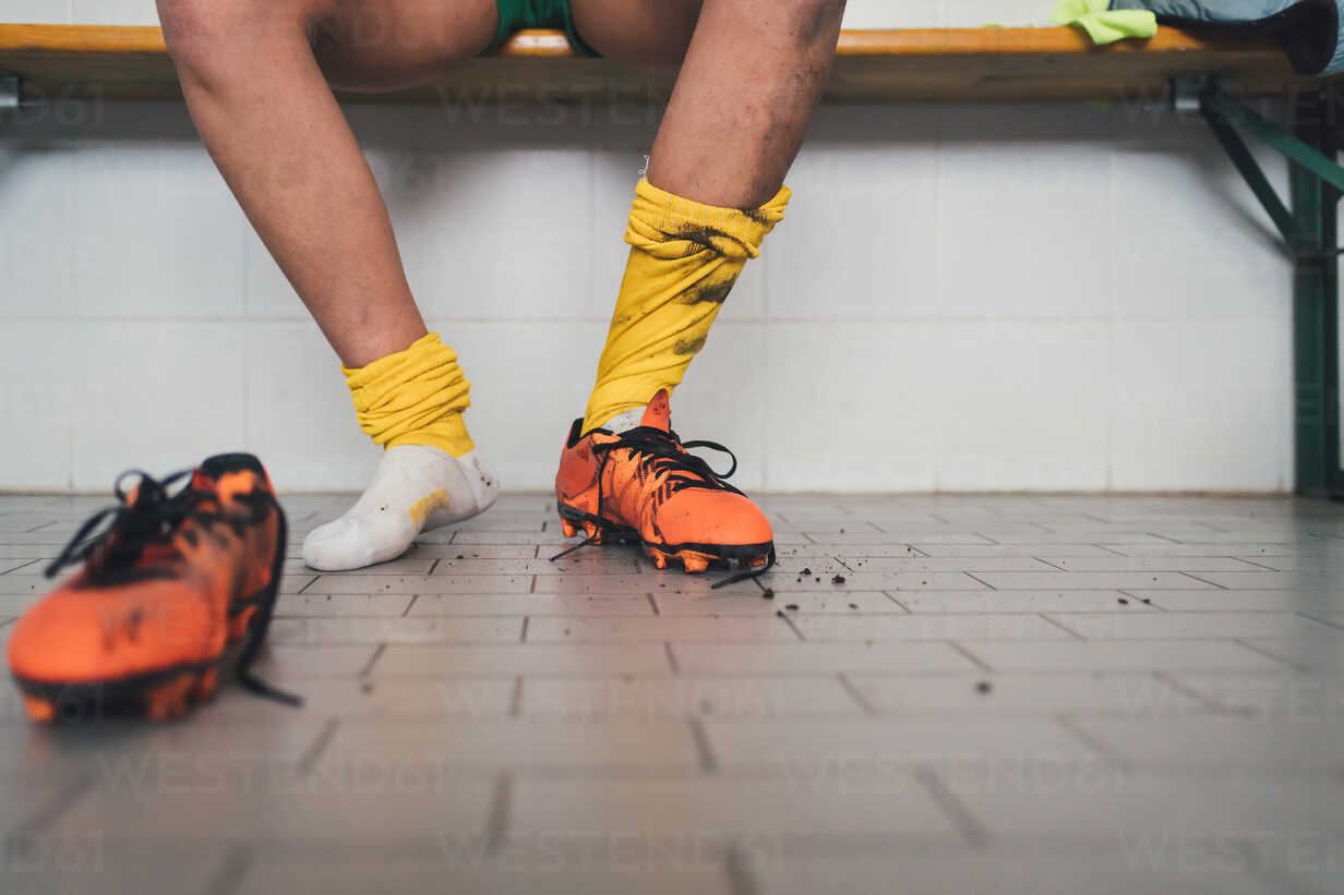 football player in one football boot in changing room CUF45236